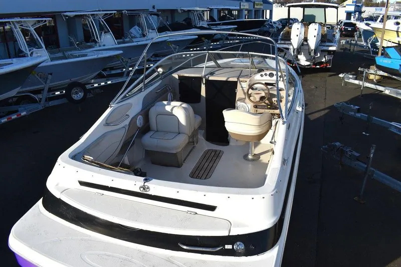 Slide: The Image of 1999 Maxum 2300SC boat with open cockpit, seating, and steering wheel, docked among other boats. - 10