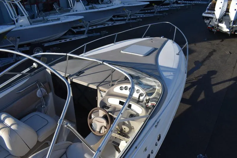 Slide: The Image of 1999 Maxum 2300SC boat with sleek design, white interior, and steering wheel, docked on trailer. - 13