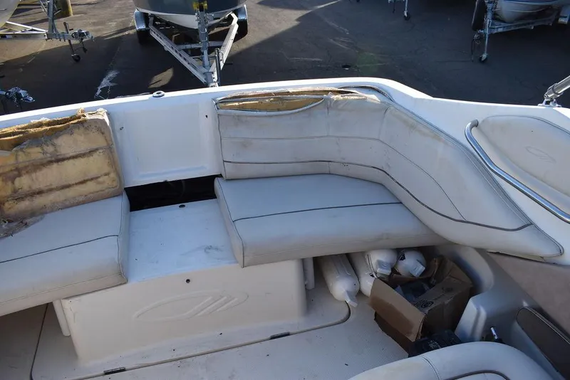 Slide: The Image of 1999 Maxum 2300SC boat interior with worn white seating and storage compartments. - 16