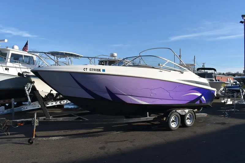 Slide: The Image of 1999 Maxum 2300SC boat with purple hull on a trailer, parked outdoors. - 3