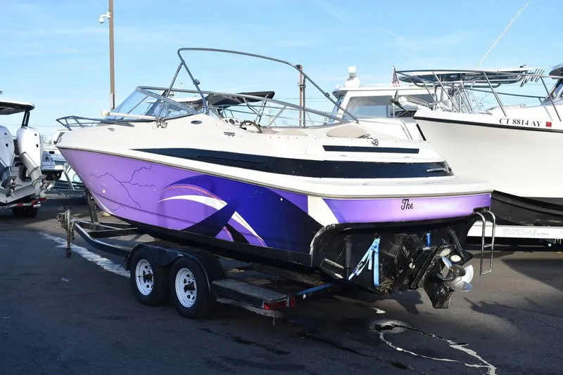 Slide: The Image of 1999 Maxum 2300SC boat with purple graphics on a trailer in a marina. - 31
