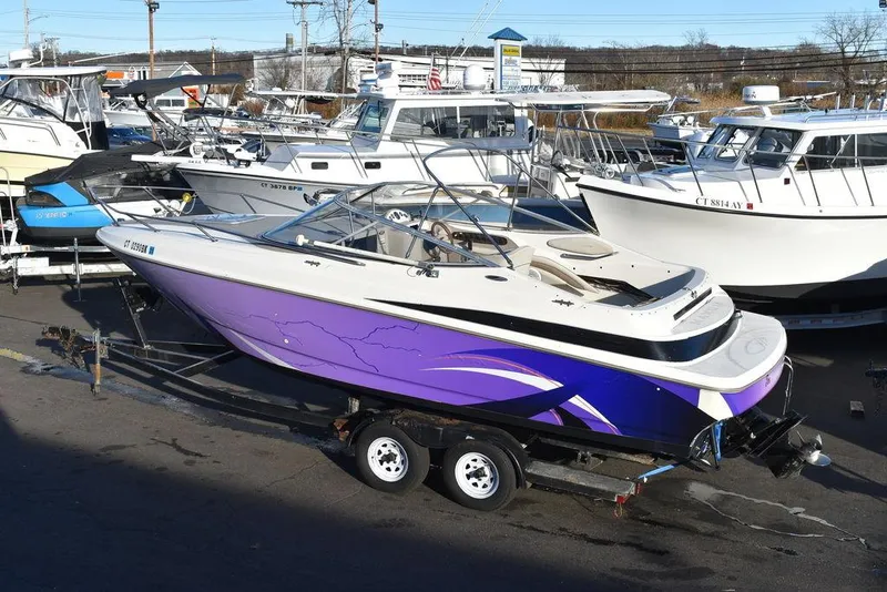 Slide: The Image of 1999 Maxum 2300SC boat with purple hull on a trailer in a marina. - 6