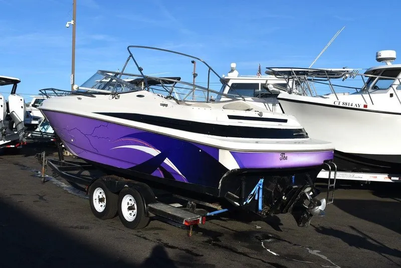 Slide: The Image of 1999 Maxum 2300SC boat with purple accents on a trailer, parked in a marina. - 7