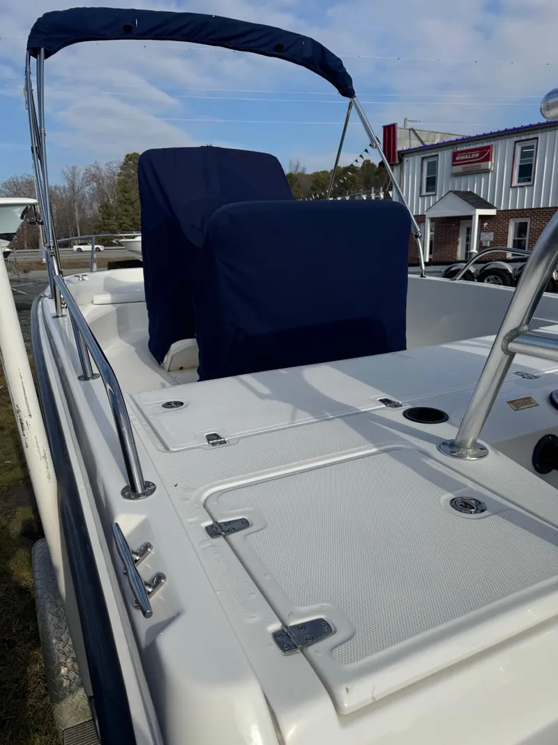 Slide: The Image of 2009 Boston Whaler 180 Dauntless boat with blue seating and canopy, docked outdoors. - 10
