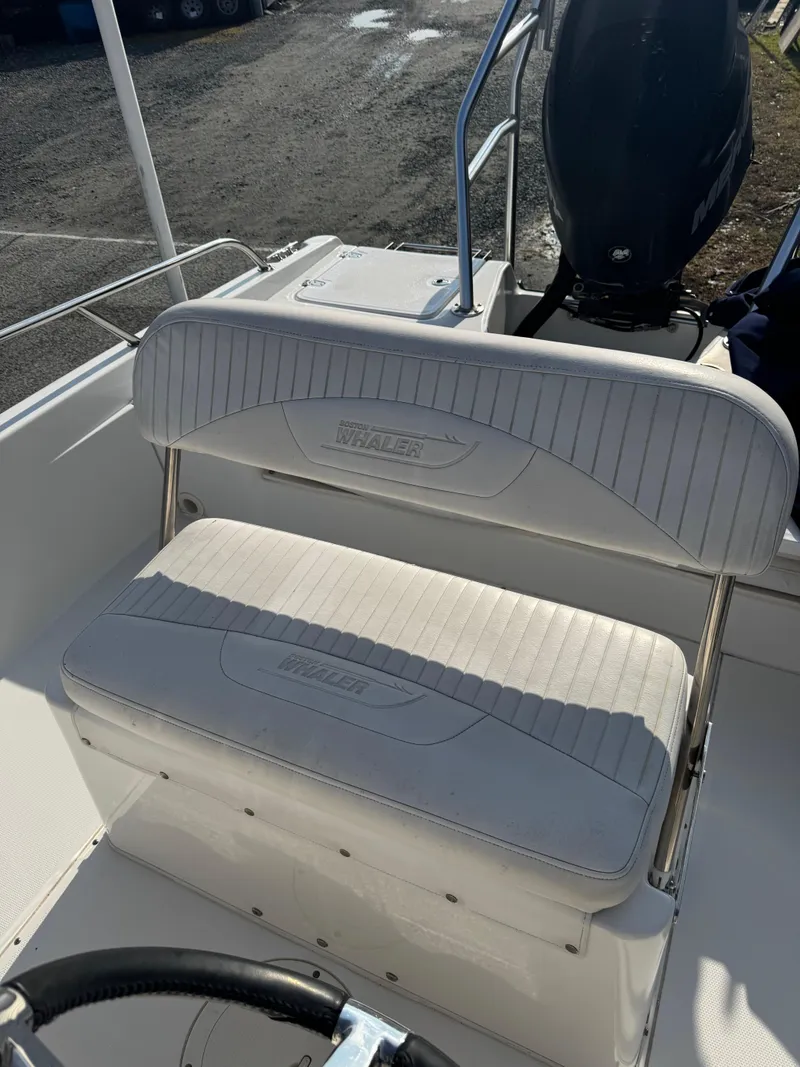 Slide: The Image of 2009 Boston Whaler 180 Dauntless boat seat and console, featuring white cushioned seating. - 7