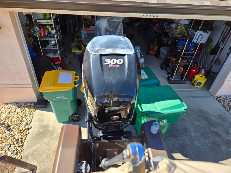 Slide: The Image of Outboard motor on a 2017 Regency 254 LE3, parked near a garage with recycling bins. - 21