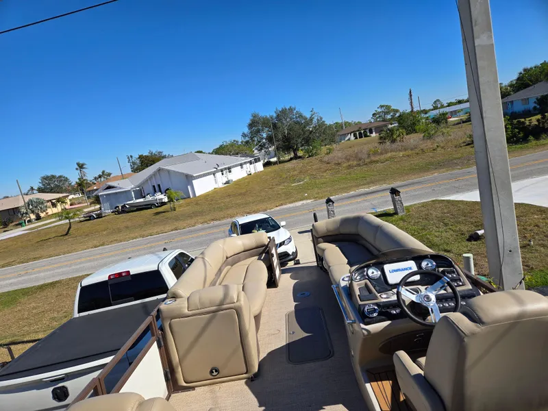 Slide: The Image of 2017 Regency 254 LE3 pontoon boat with beige seating, parked near residential area. - 7