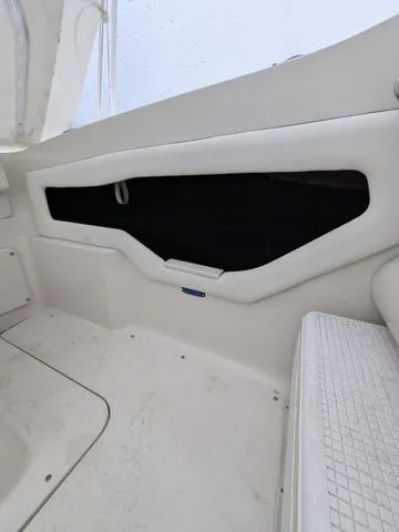 Slide: The Image of Interior view of a 1999 Sea Ray 215 Express Cruiser boat, featuring white seating and paneling. - 27