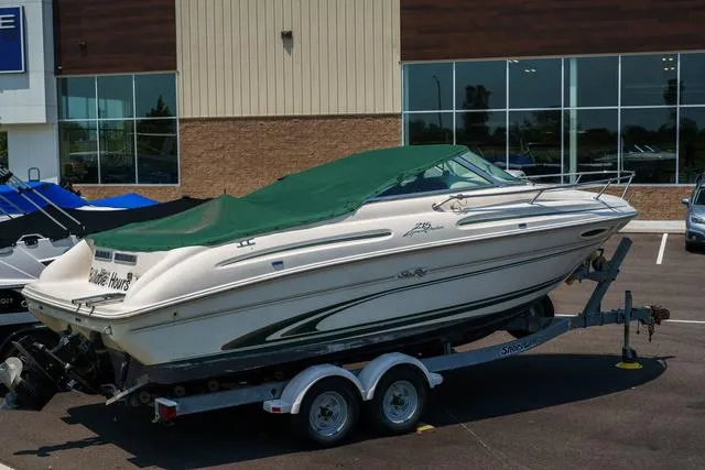 Slide: The Image of 1999 Sea Ray 215 Express Cruiser boat on trailer with green cover. - 3