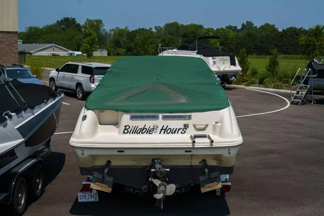 Slide: The Image of 1999 Sea Ray 215 Express Cruiser with green cover, named "Billable Hours," parked in a lot. - 4