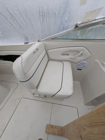 Slide: The Image of 1999 Sea Ray 215 Express Cruiser interior with white seating and speaker. - 8
