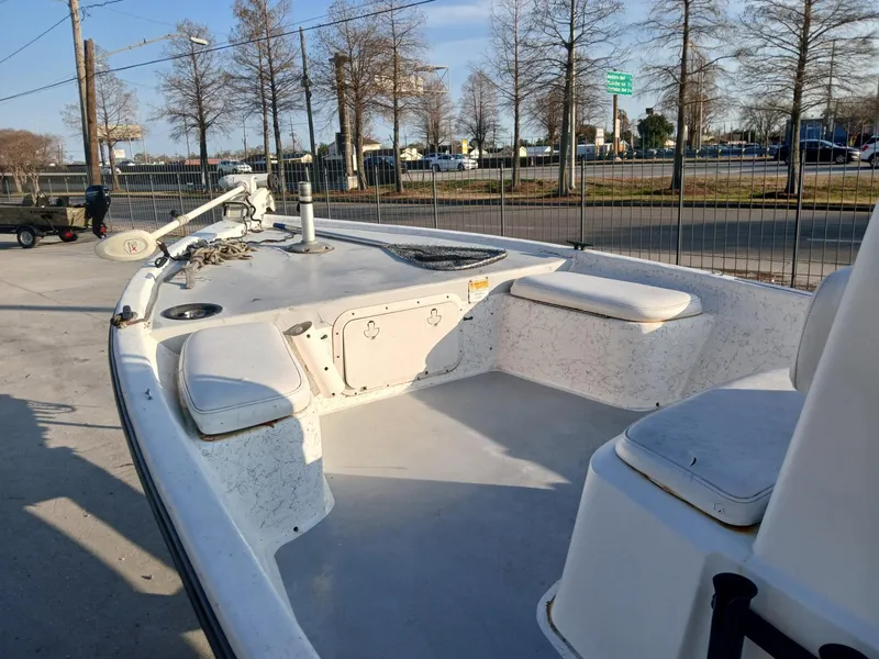 Slide: The Image of 2006 Kenner 21 boat on trailer, parked outside a modern building with an American flag. - 2