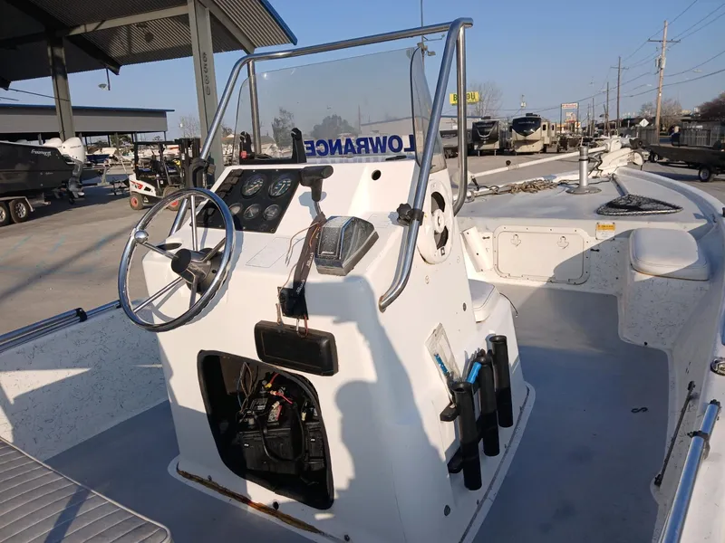 Slide: The Image of 2006 Kenner 21 boat with outboard motor, parked on a trailer in a lot. - 6