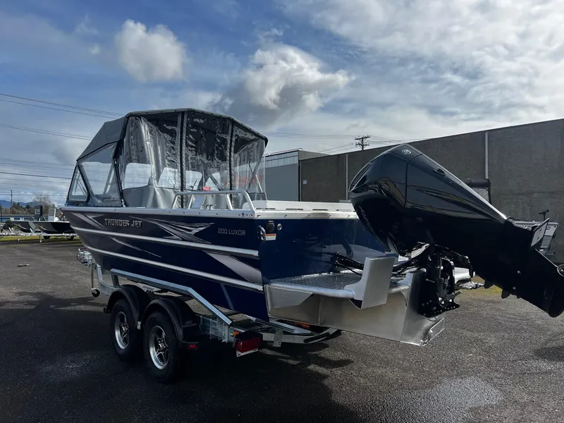 Slide: The Image of 2025 Thunder Jet 210 Luxor boat with outboard motor on trailer, parked outdoors. - 10