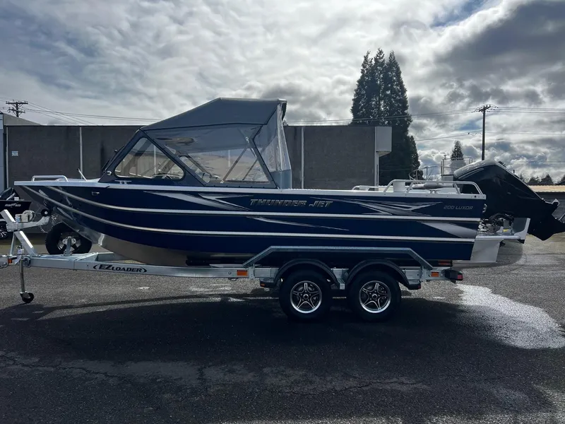 Slide: The Image of 2025 Thunder Jet 210 Luxor boat on trailer, parked outdoors under cloudy sky. - 11
