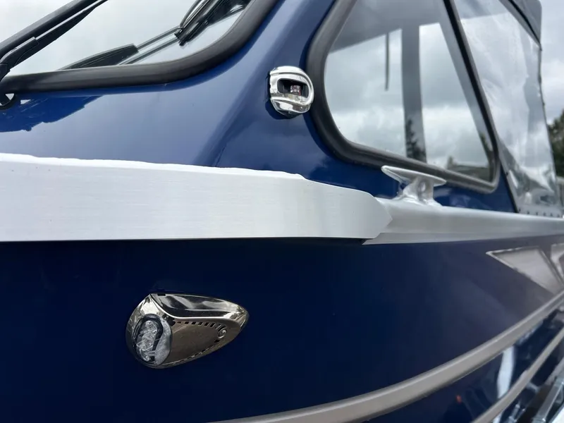 Slide: The Image of 2025 Thunder Jet 210 Luxor boat, blue exterior, close-up of window and chrome details. - 12