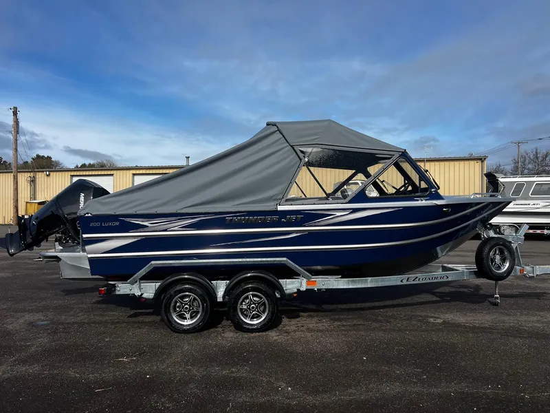Slide: The Image of 2025 Thunder Jet 210 Luxor boat with gray canopy on a trailer. - 2