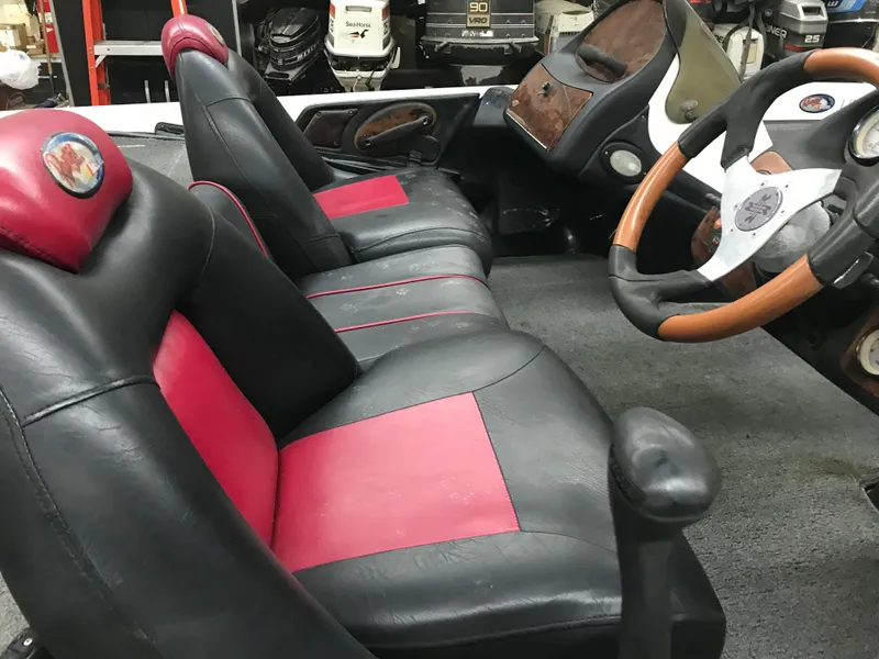 Slide: The Image of 2004 Ranger 519 VX/VS boat interior with black and red seats, wooden steering wheel. - 10