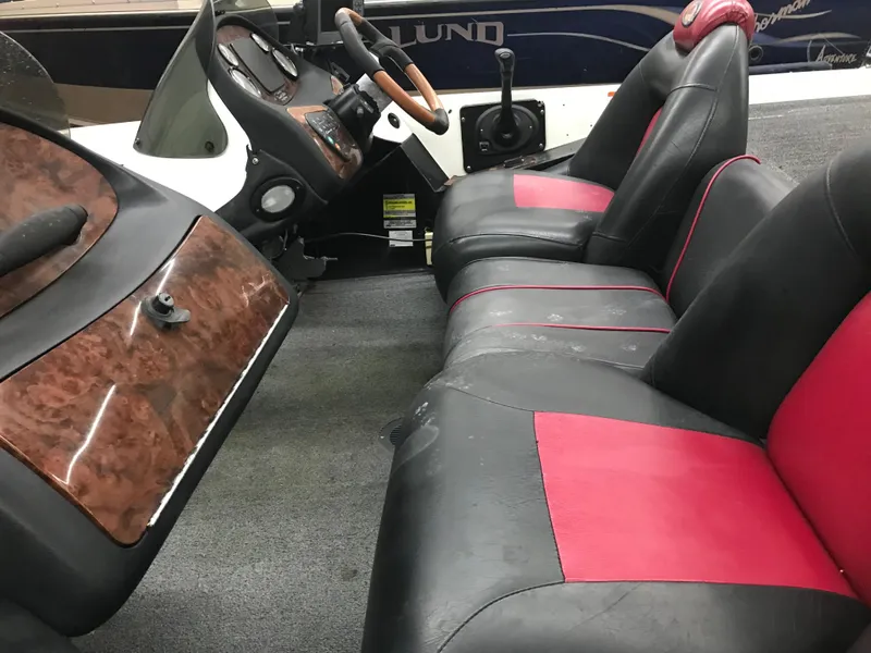 Slide: The Image of 2004 Ranger 519 VX/VS boat interior with black and red seating, wood accents, and steering console. - 18