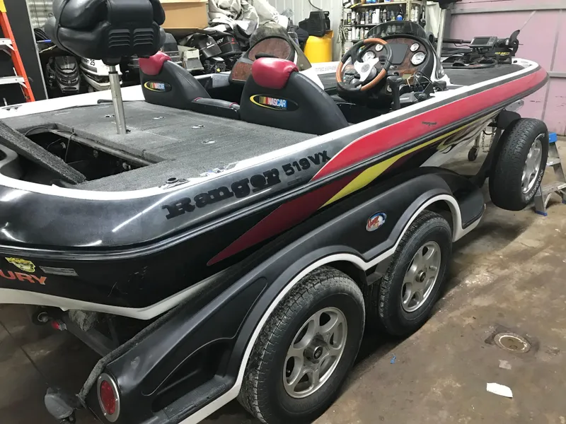 Slide: The Image of 2004 Ranger 519 VX/VS boat in garage, dual seats, steering wheel, and trailer. - 3