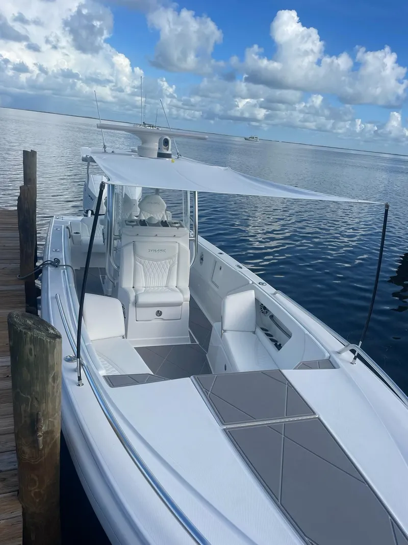 Slide: The Image of 2024 Dynamic D-305V boat docked by calm waters under a cloudy sky. - 2