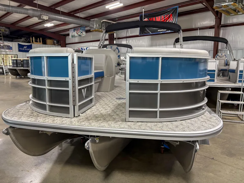 Slide: The Image of 2025 Trifecta 24 UL LE pontoon boat in showroom, featuring blue and silver design. - 11