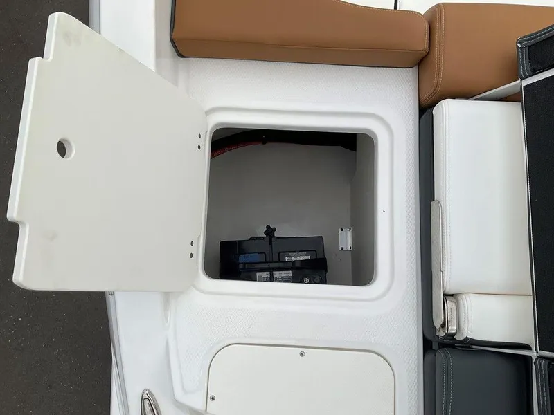 Slide: The Image of 2025 Chaparral 23 SSi boat storage compartment with open hatch and visible battery. - 12