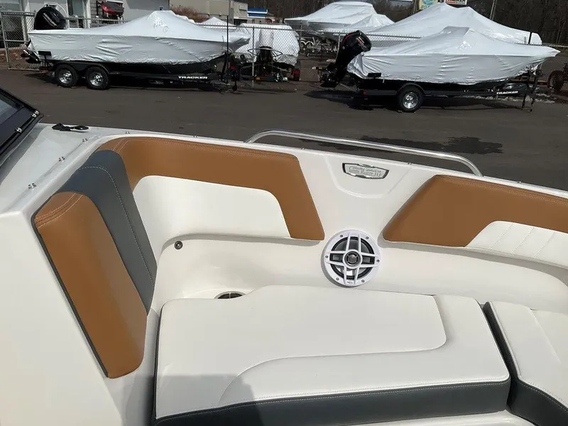 Slide: The Image of 2025 Chaparral 23 SSi boat interior with tan and gray seating, docked with covered boats nearby. - 45