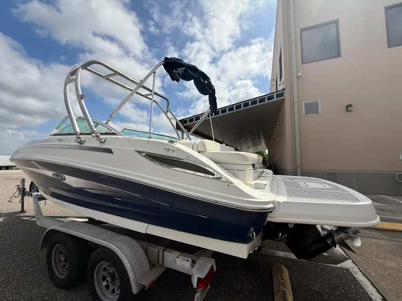 Slide: The Image of 2008 Sea Ray 210 Sundeck boat on trailer, parked outdoors under a cloudy sky. - 19