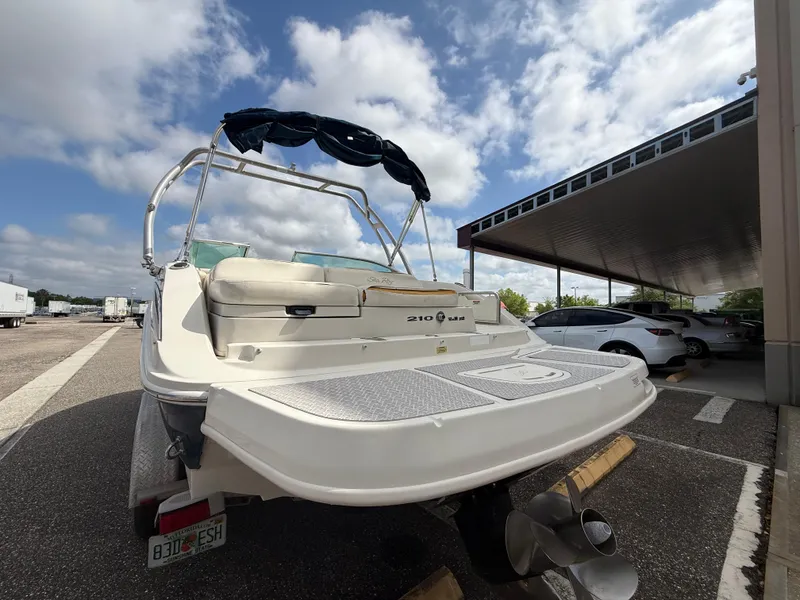 Slide: The Image of 2008 Sea Ray 210 Sundeck boat parked, rear view, under a partly cloudy sky. - 21
