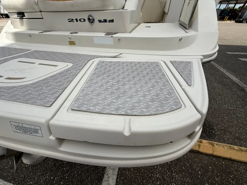 Slide: The Image of 2008 Sea Ray 210 Sundeck boat with gray deck padding, rear view. - 29