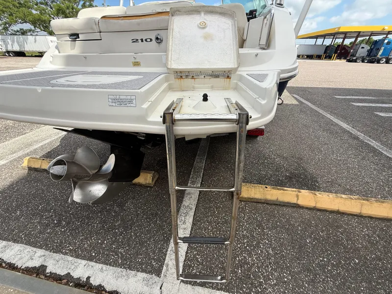 Slide: The Image of 2008 Sea Ray 210 Sundeck boat with extended swim ladder and propeller in parking lot. - 30