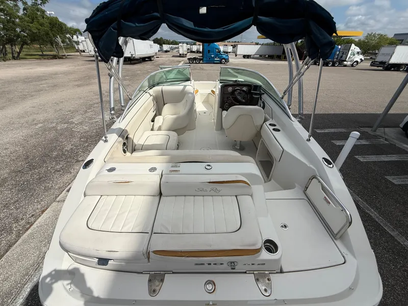 Slide: The Image of 2008 Sea Ray 210 Sundeck boat with white seating and canopy in a parking area. - 31
