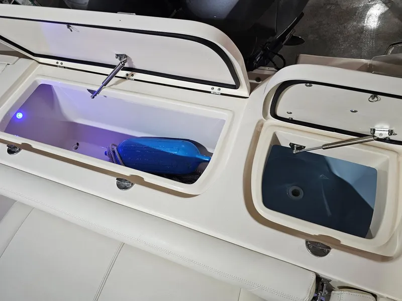 Slide: The Image of 2015 Grady-White Freedom 275 boat storage compartments with open lids and interior lighting. - 18