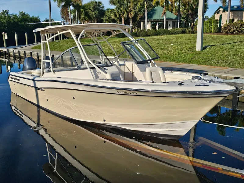Slide: The Image of 2015 Grady-White Freedom 275 boat docked on calm water, surrounded by lush greenery. - 2