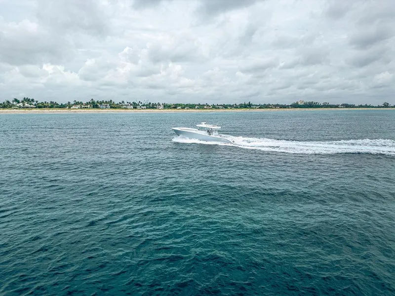 Slide: The Image of 2019 Yellowfin 42 boat cruising on open water near a tropical shoreline. - 12