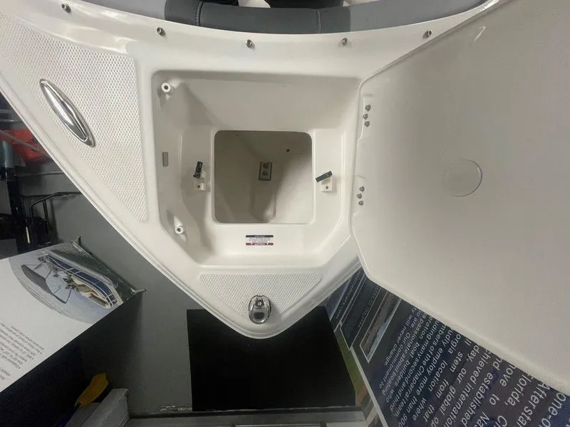 Slide: The Image of 2025 Chaparral 23 SSi boat storage compartment, open lid, white interior, showroom display. - 16