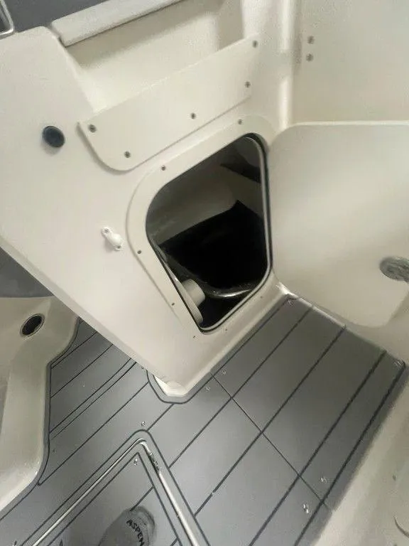 Slide: The Image of 2025 Chaparral 23 SSi boat interior storage compartment with gray flooring. - 23