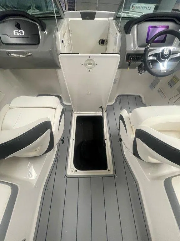 Slide: The Image of 2025 Chaparral 23 SSi boat interior with open storage compartment and modern dashboard. - 24