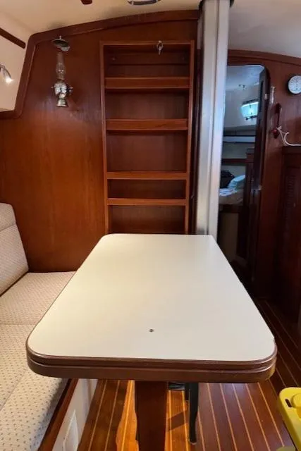 Slide: The Image of Interior of a 1995 Island Packet 37 sailboat with wooden shelves and a dining table. - 21