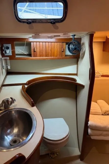Slide: The Image of 1995 Island Packet 37 sailboat bathroom with sink, toilet, and wooden cabinetry. - 25