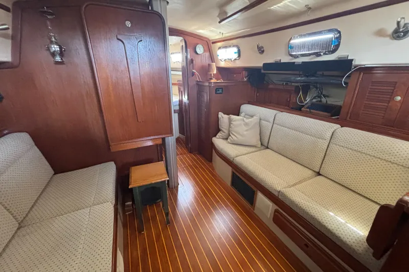 Slide: The Image of Interior of 1995 Island Packet 37 sailboat with wooden flooring and cushioned seating. - 9