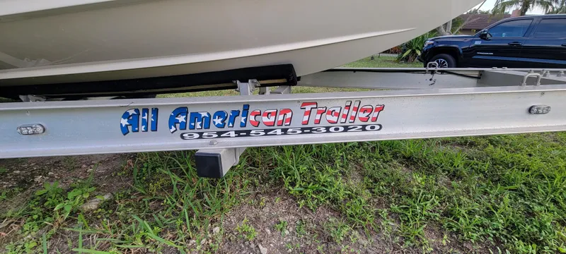 Slide: The Image of Trailer with "All American Trailer" branding, parked on grass, near a Regal LS2 boat. - 12