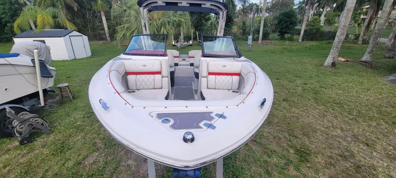 Slide: The Image of 2021 Regal LS2 boat with open bow seating, parked on grass with palm trees. - 19