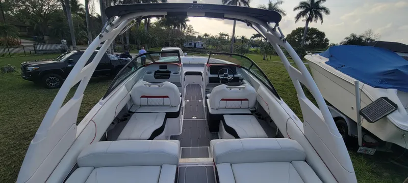 Slide: The Image of 2021 Regal LS2 boat interior with white seating, parked outdoors near palm trees. - 21