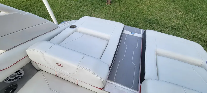 Slide: The Image of 2021 Regal LS2 boat interior with white seating and gray flooring, set against a grassy background. - 29