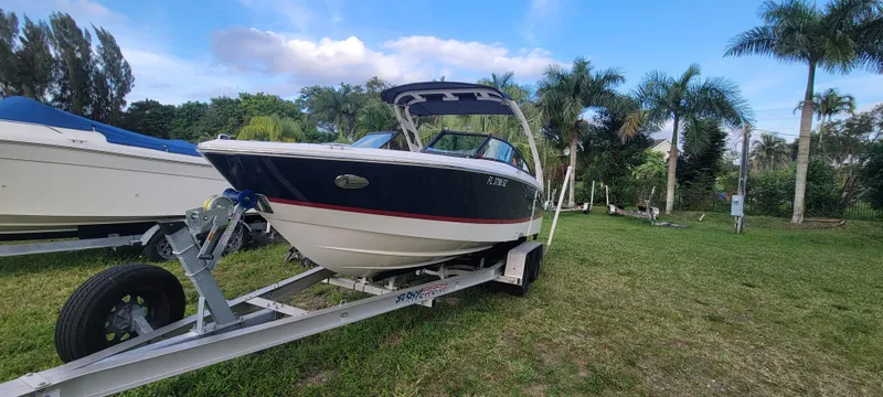 Slide: The Image of 2021 Regal LS2 boat on trailer, parked on grass with palm trees in the background. - 4