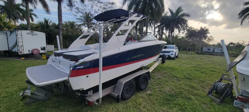 Slide: The Image of 2021 Regal LS2 boat on trailer, parked on grass with palm trees in background. - 5