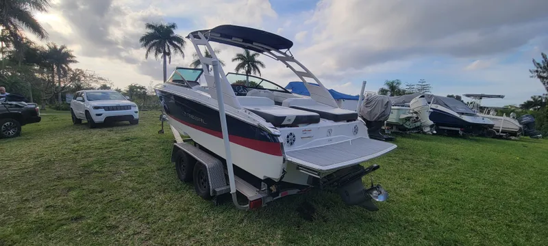 Slide: The Image of 2021 Regal LS2 boat on trailer, parked on grass with palm trees in background. - 6