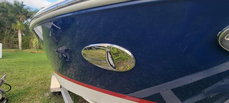 Slide: The Image of 2021 Regal LS2 boat, blue hull with chrome detailing, parked on grass. - 8